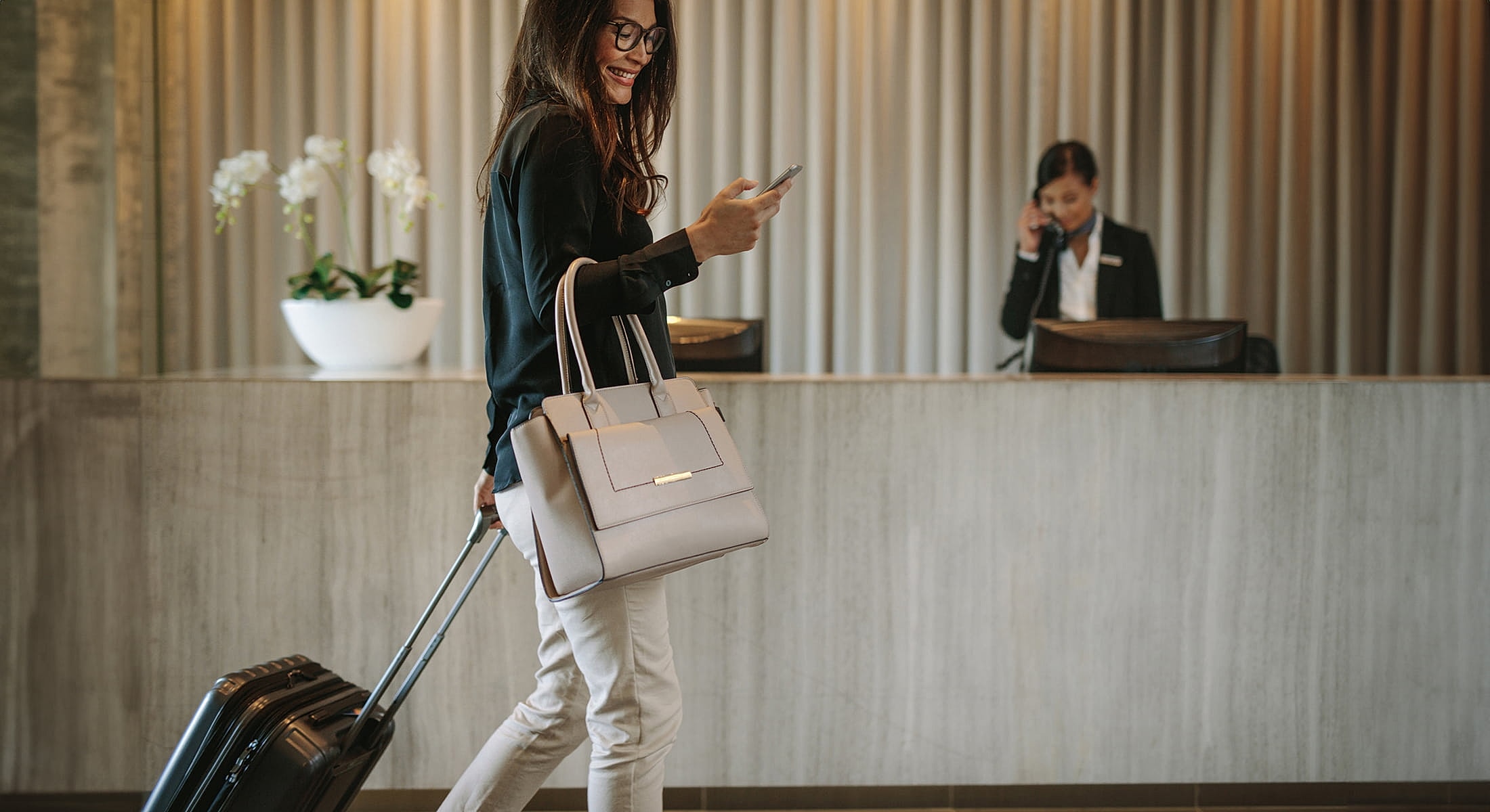 Woman checking phone at hotel reception.