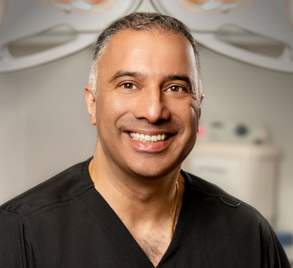 Smiling medical professional in surgical attire.