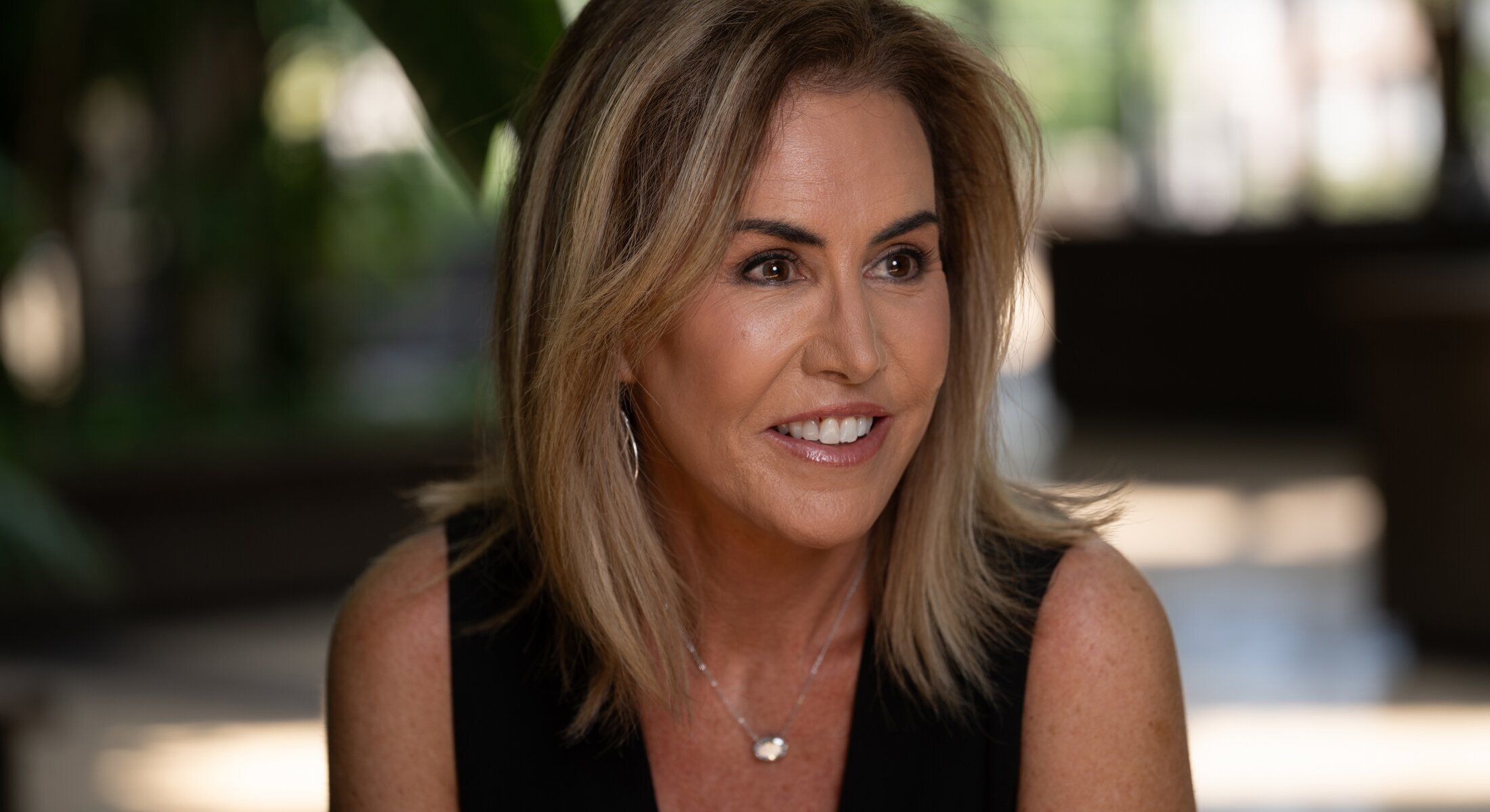 Smiling woman outdoors with blurred background.