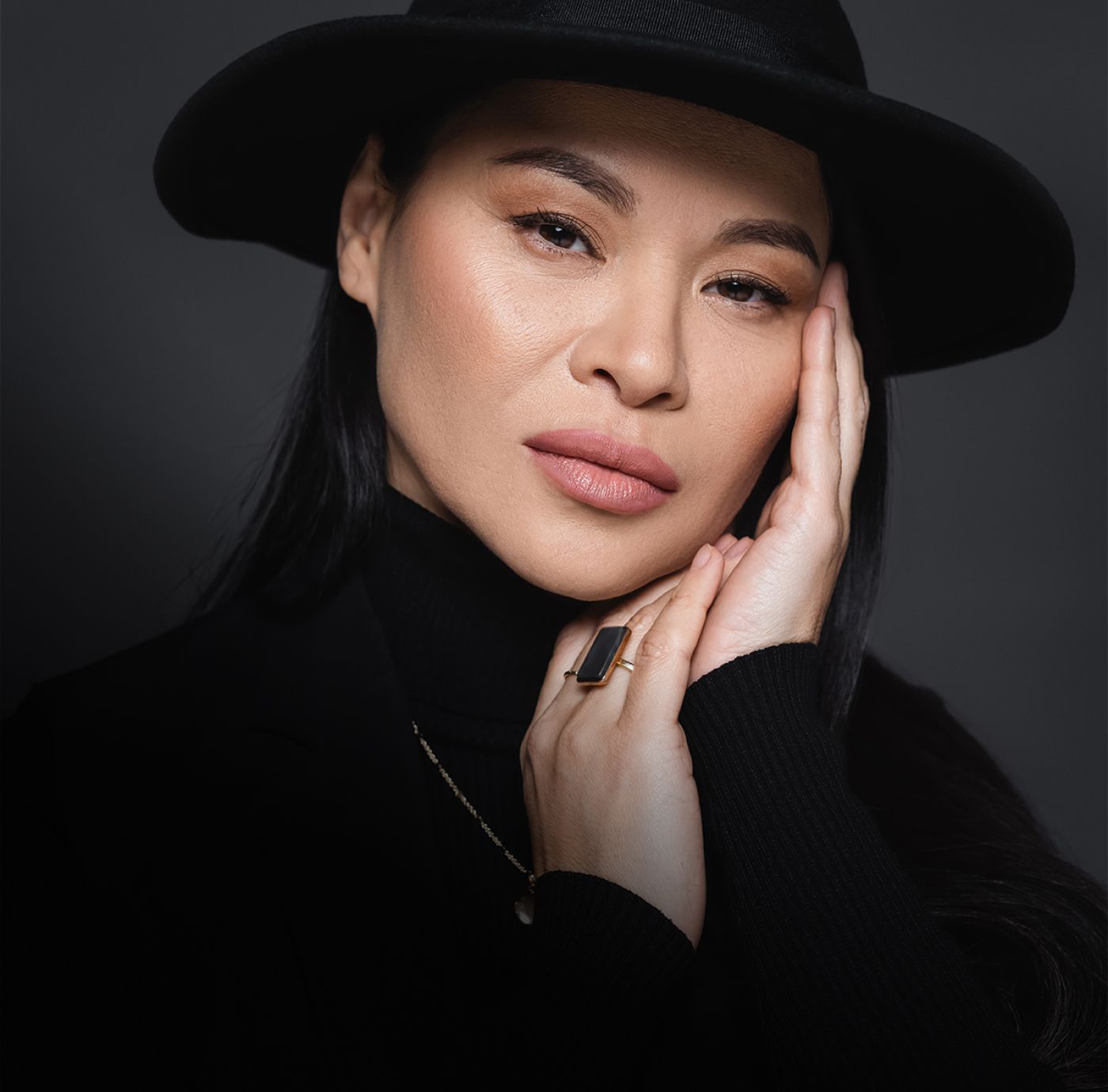 Woman in black attire with a stylish hat.