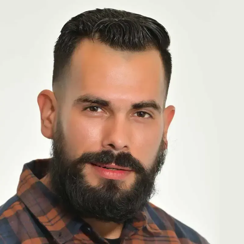 Bearded man in plaid shirt, neutral background.