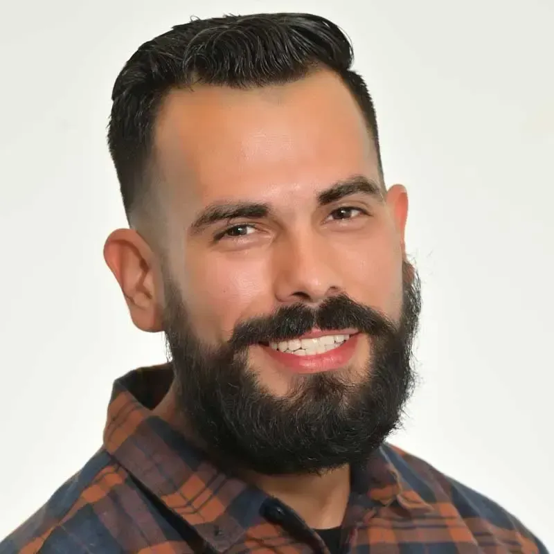 Smiling man with beard in plaid shirt.