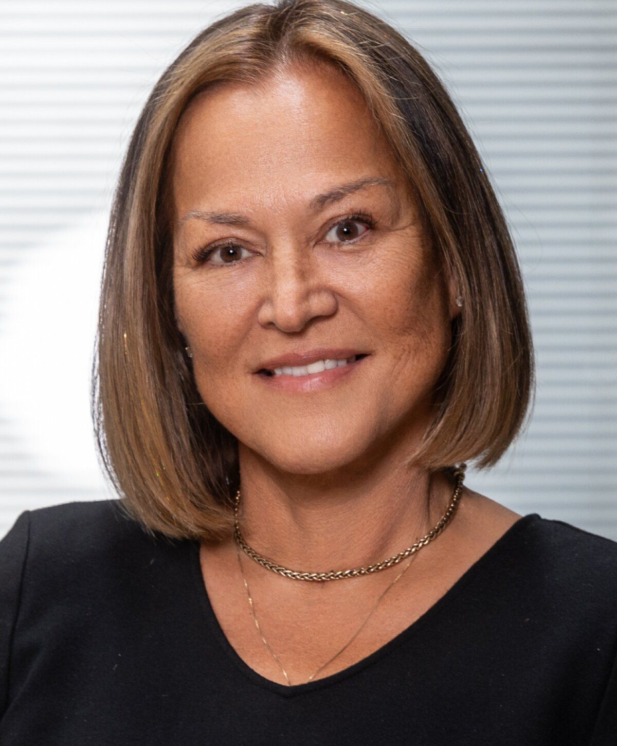 Woman with bob haircut smiling in black shirt.