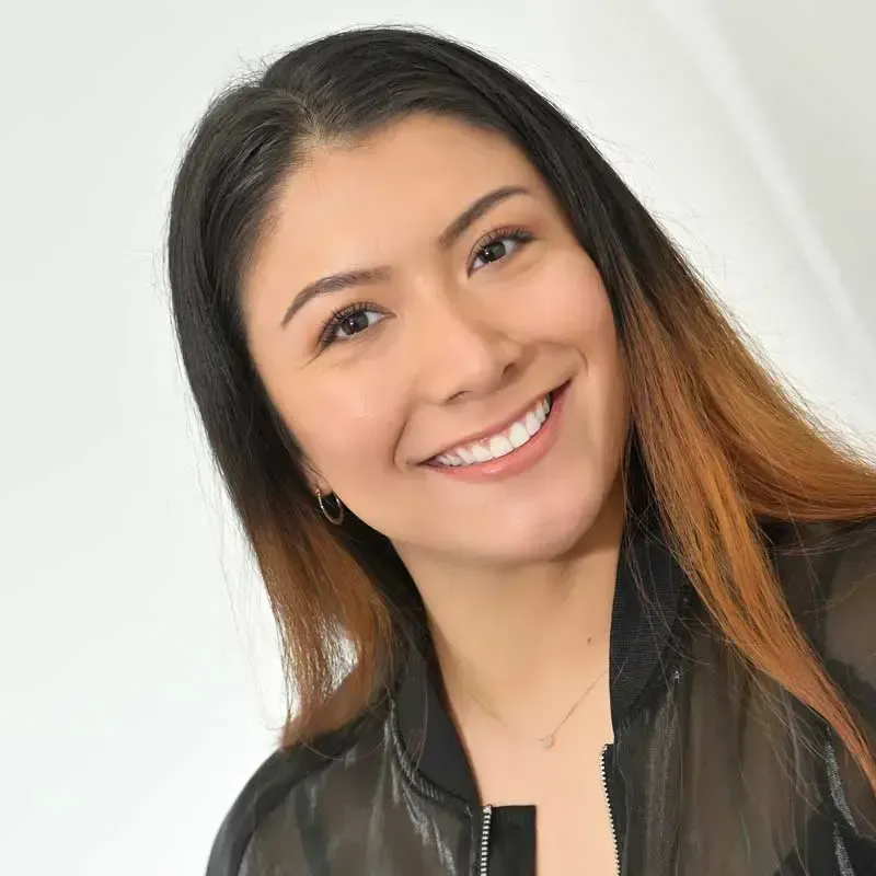 Smiling woman with long, dark hair indoors.