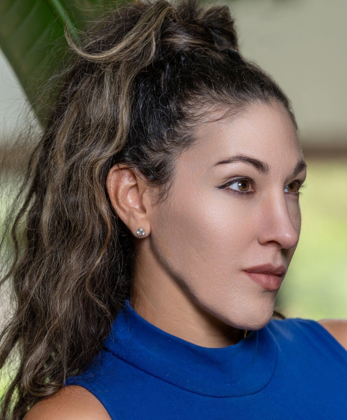 Woman in blue top with curly hair profile.