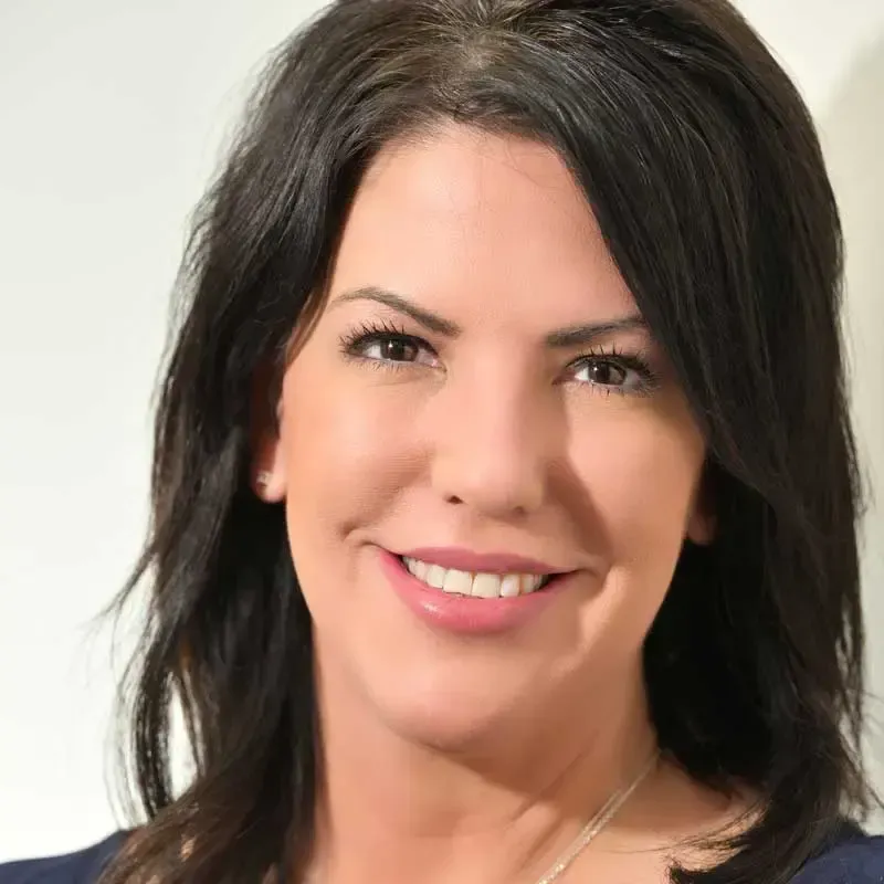 Smiling woman with dark hair and necklace.