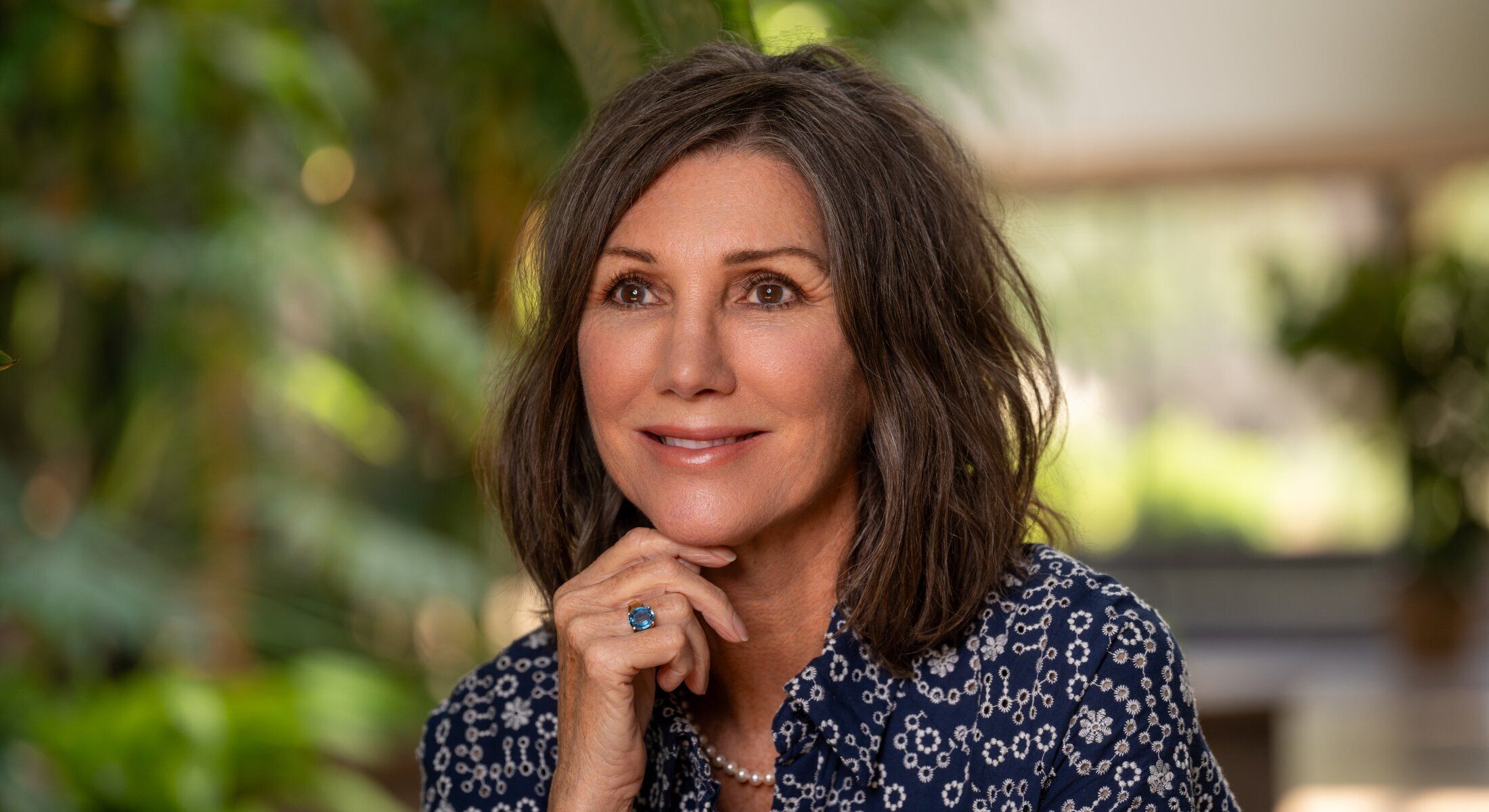 Woman smiling in a green, natural setting.