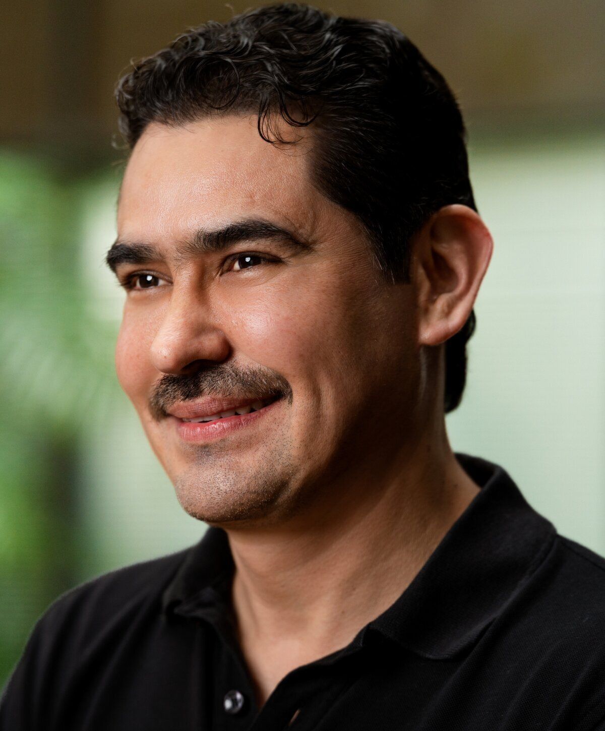 Smiling man in a black polo shirt.