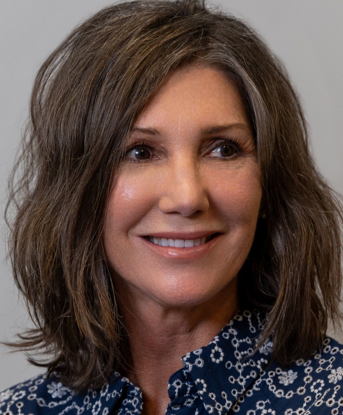 Smiling woman with shoulder-length hair and blouse.