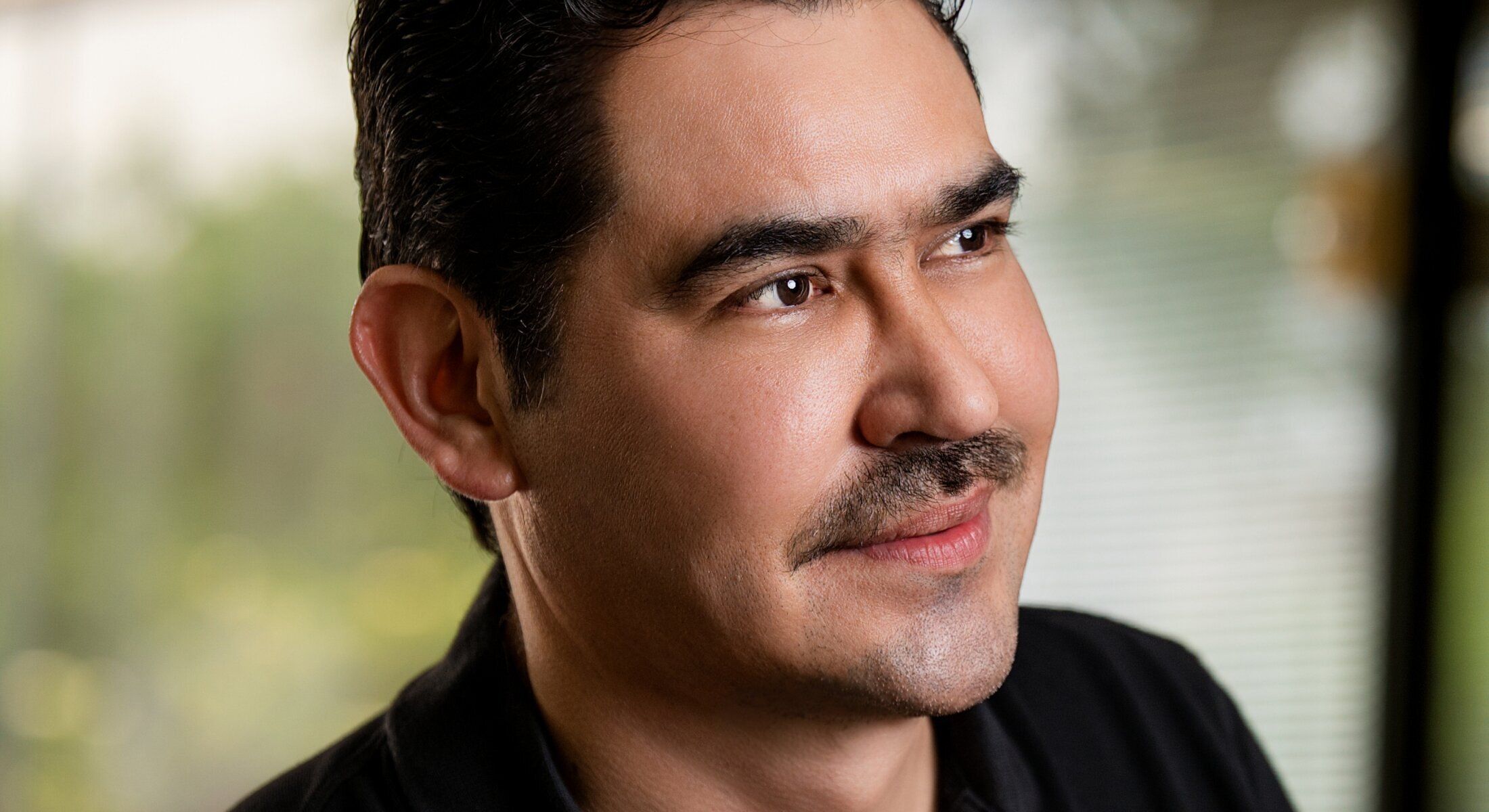 Man smiling with short hair and mustache.