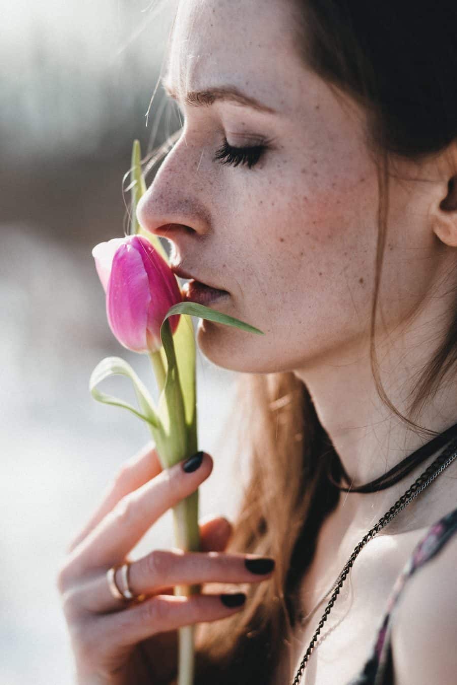 portrait of woman closing eyes and smelling a tulip