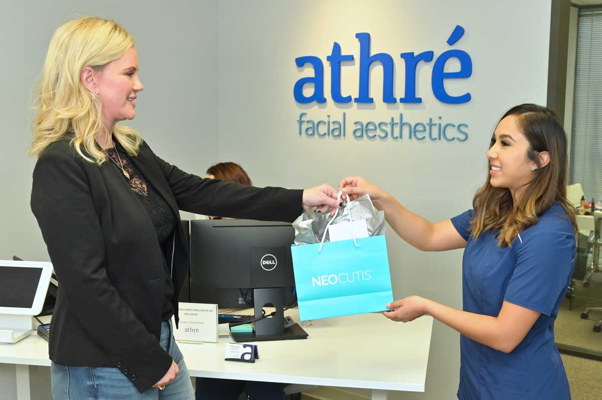 Athré Facial Plastics staff member handing patient a product shopping bag..