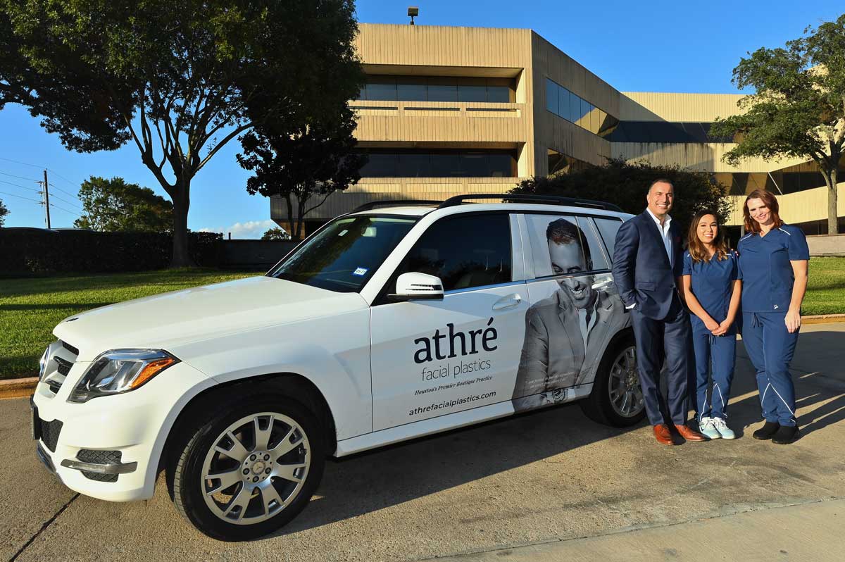 Dr. Athre and staff standing next to vehicle decorated with Athre Facial Plastics decal.