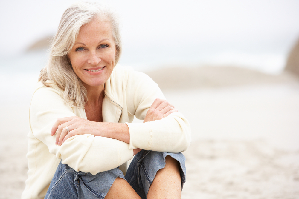 Beautiful older woman smiling sitting on the beach