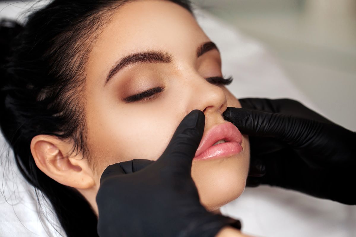 woman laying down and gloved hands touching her lips